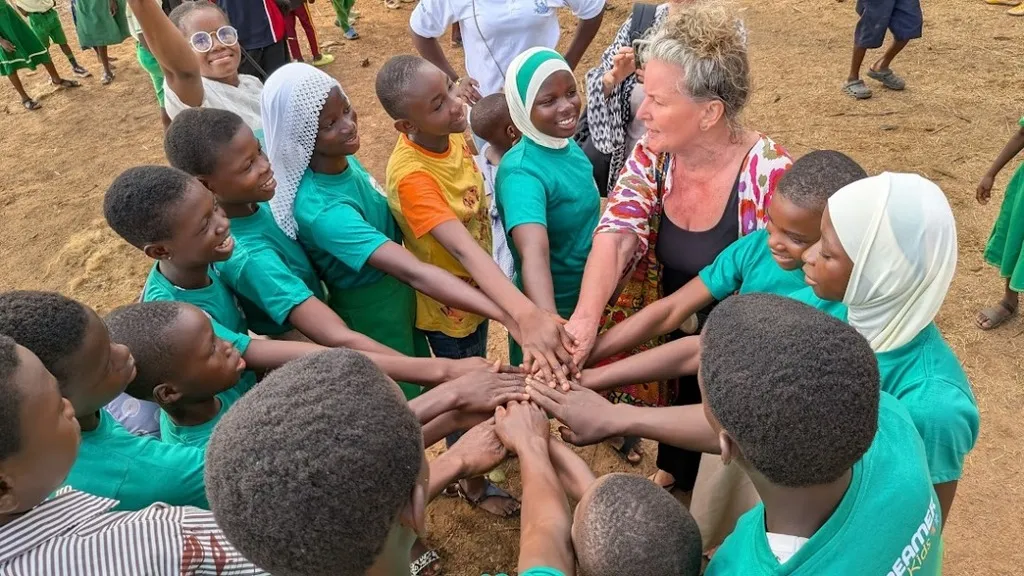 A circle of hands joined at Dream Village — schoolchildren and visitors together